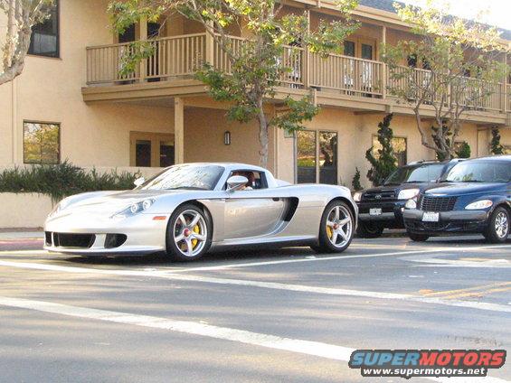 Silver sports car, black SUV, and blue PT Cruiser parked on street