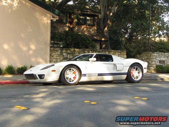White Ford GT parked on street, blue racing stripes on side