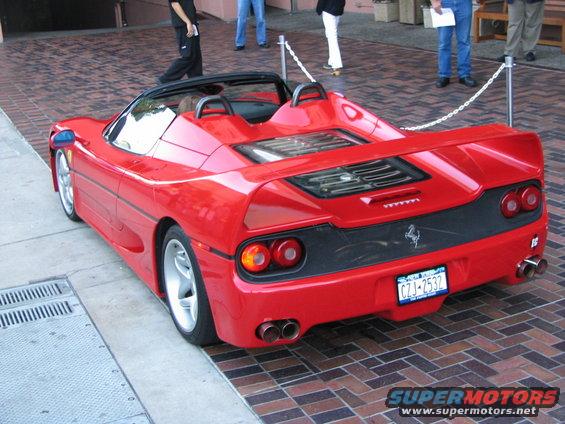 Red convertible sports car, rear view, with dual exhaust pipes and a Ferrari badge