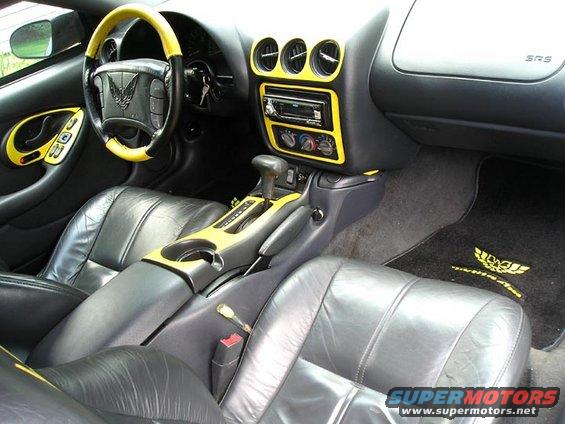 Car interior with black leather seats and yellow trim on dashboard and steering wheel