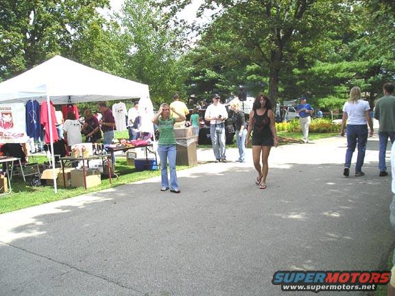 Outdoor event with tents selling merchandise and people walking around