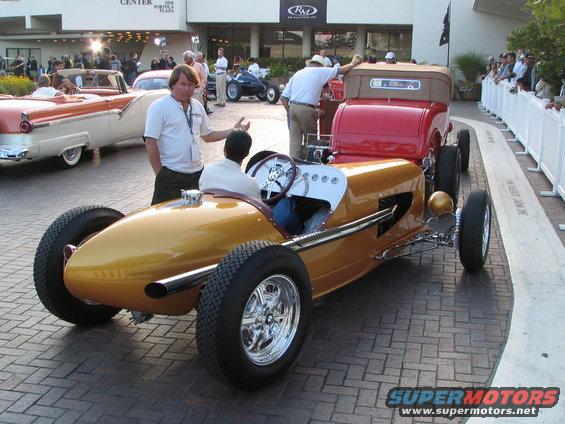 Gold vintage race car with exposed wheels and a tan interior