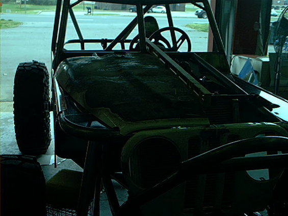 Off-road vehicle with roll cage and large tires, partially covered