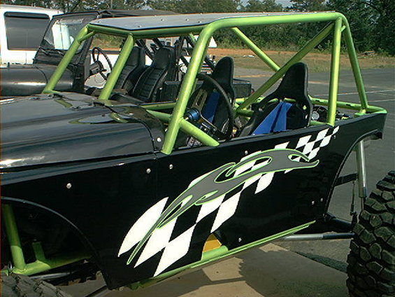Black off-road buggy with green roll cage, racing seats, and checkered flag graphics