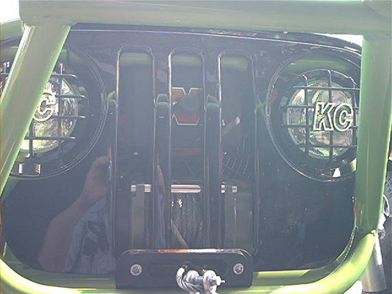 Black Jeep grille with vertical slots, KC lights, and a winch mounted below