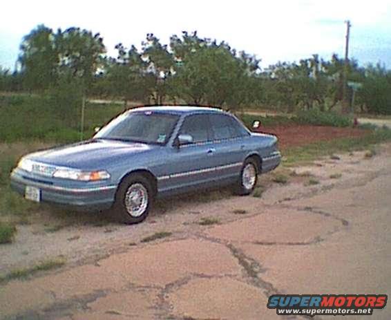 1994 Ford Crown Victoria parked on a dirt road with trees in the background
