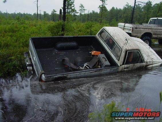 Truck stuck in murky water with another truck behind it