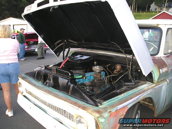 1960s truck engine bay with hood open, showing blue engine block and parts