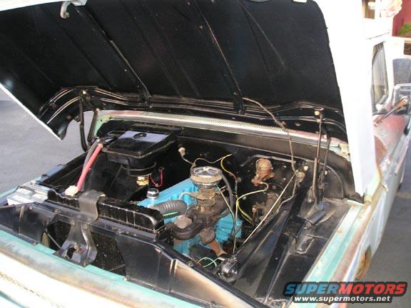 Engine bay of a classic truck with hood open. Blue engine block visible