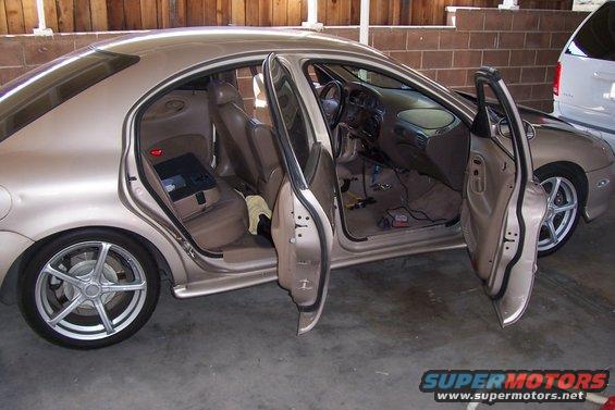 Tan sedan with all doors open, interior visible, wires and equipment on floor