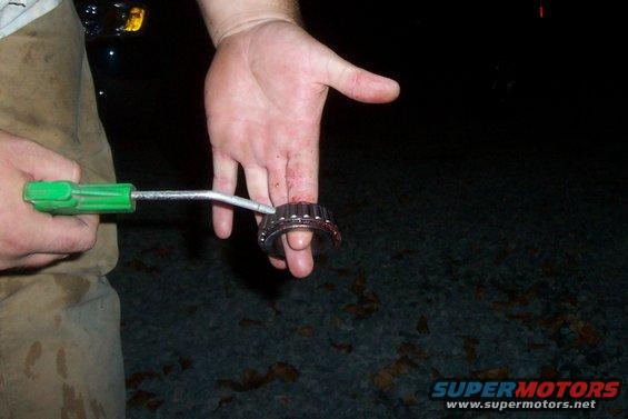 Hand holding a wheel bearing with a tool