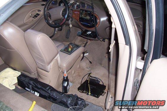 Interior of a 1998 Mercury Sable, showing tan seats, dashboard, and aftermarket audio equipment on the floor