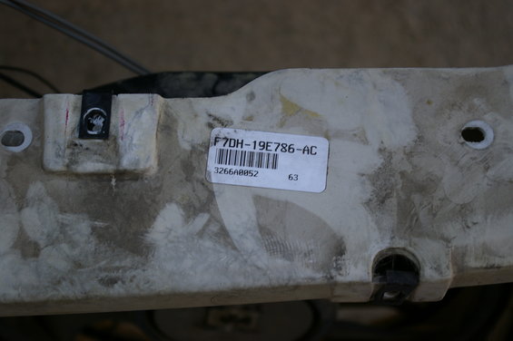 Close-up of a white plastic part with a label that reads F7DH-19E786-AC and a barcode