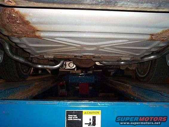 Underside view of a vehicle with dual exhaust and rusty frame