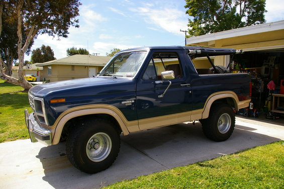 1986 Ford Bronco parked in a driveway next to a garage