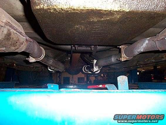 Underside of a vehicle showing dual exhaust pipes and suspension components