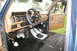 1986 Ford Bronco - The interior of a blue vehicle, a dashboard, steering wheel, and floor with a manual transmission shifter.