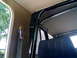 1989 Ford Bronco - The interior of a vehicle shows a roll cage structure and a dark-colored seat with a seatbelt.