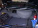 2002 Ford Crown Victoria - The trunk of a black 2002 Ford Crown Victoria contains a spare tire, fire extinguisher, and various bags.