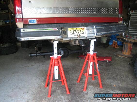 1990 Ford Bronco rear bumper and axle assembly supported by red jack stands