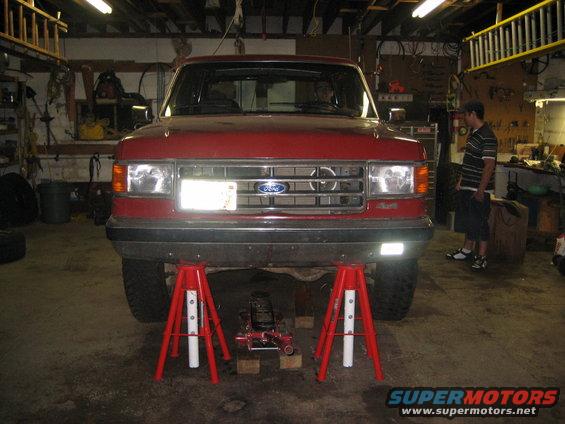 1990 Ford Bronco front end on red jack stands in a garage