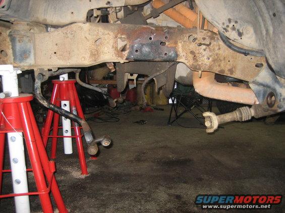 rusted vehicle frame supported by red jack stands, with suspension components visible