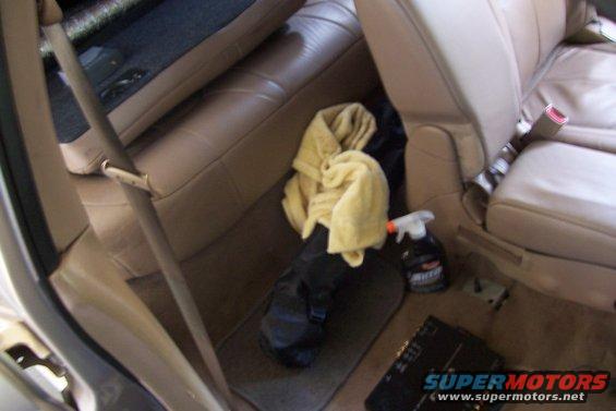 Tan leather car seats and floor mats with a yellow towel and spray bottle