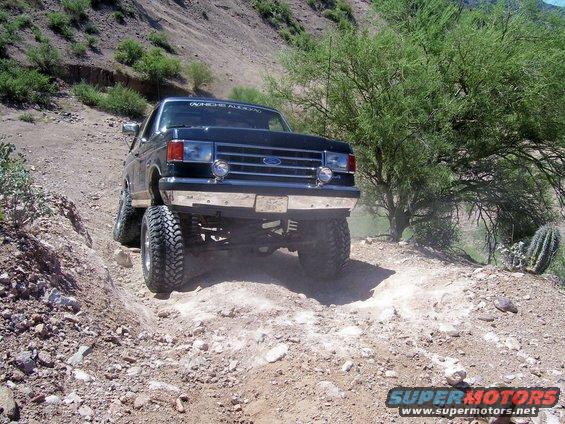 Black Ford Bronco with lifted suspension driving on a rocky, off-road trail