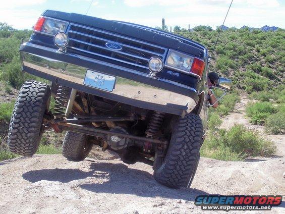 Black Ford Bronco with lifted suspension and off-road tires tilted on a dirt trail