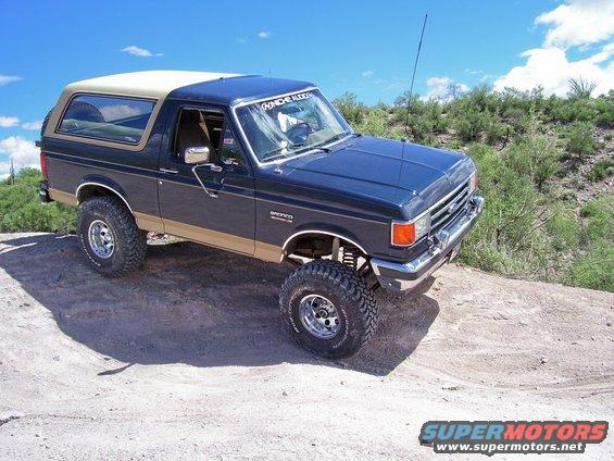 1991 Ford Bronco with lifted suspension and off-road tires on a dirt trail