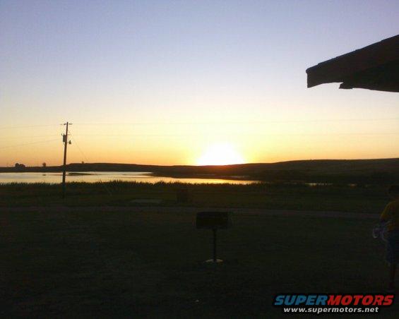 Sunset over a lake with a utility pole in the foreground and a person on the right