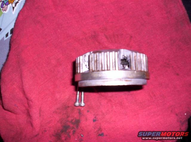 Metal part with vertical fins and two screws attached, resting on a red cloth