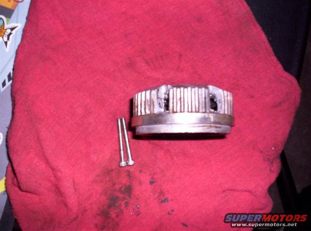 metal part with splines and two screws on a red cloth