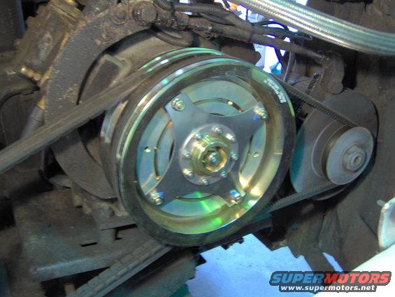 close-up of a vehicle's engine pulley system with belts and a shiny metal component