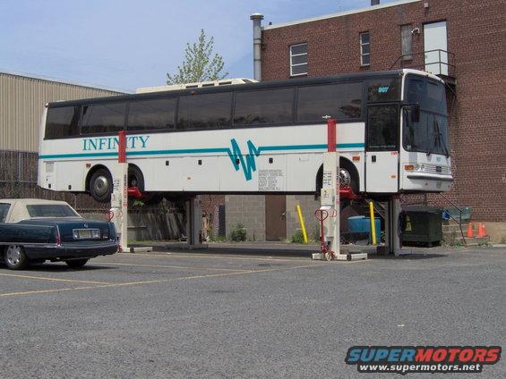 Bus on a lift with a car parked nearby
