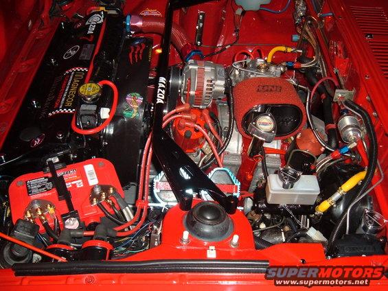 Engine bay with Mazda engine components, red battery, and custom wiring