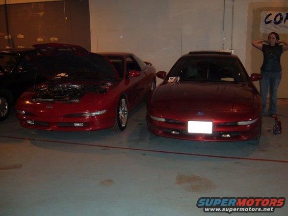 Front view of a red 1991 Ford Probe with hood open, another red 1991 Ford Probe beside it