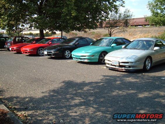 Silver Ford Probe parked in a line with other similar cars, front 3/4 view