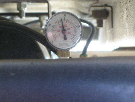 Close-up of a pressure gauge with PSI markings, connected to a hose