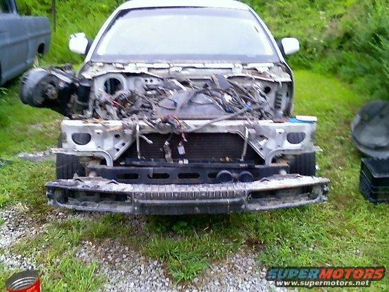 White 2002 Ford Crown Victoria front end disassembled, showing exposed engine components and wiring