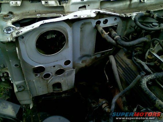 Firewall and engine bay of a disassembled vehicle, showing hoses and metal components
