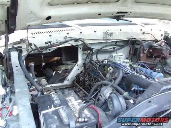 White 1979 Ford Bronco engine bay with hood open, showing engine components, battery, and wiring