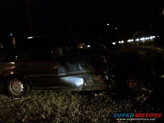 Dark sedan, side view, passenger door heavily damaged