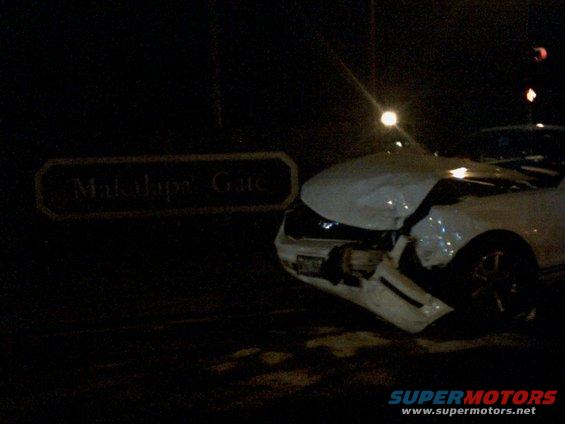 Damaged white car front end near a sign that says 'Makalapa Gate'
