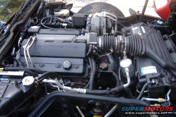 1994 Chevrolet Corvette engine bay with V8 engine, air intake, and hoses visible. 'CORVETTE' is written on the engine cover
