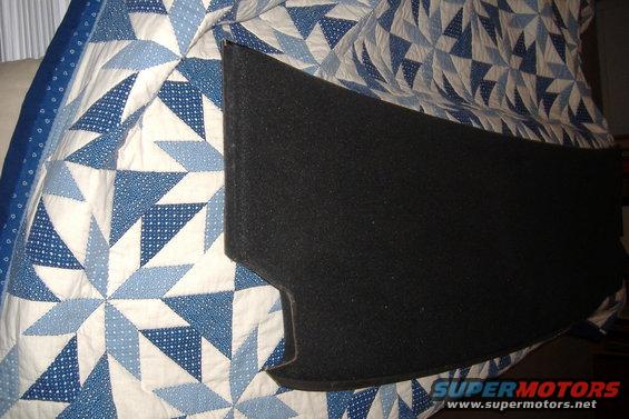 Black carpeted car part on a blue and white geometric quilt