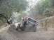1979 Ford Bronco - A red SUV navigates a steep dirt path, kicking up dust.
