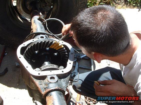 Differential assembly with gears being inspected by a person. Rusty metal casing
