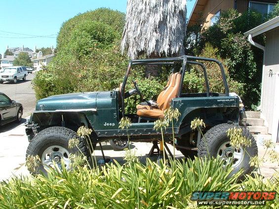 Green 1994 Jeep YJ Wrangler on jack stands, side view, with aftermarket wheels and roll cage
