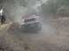 1979 Ford Bronco - A red SUV navigates a dusty, off-road trail with a person watching from the side.